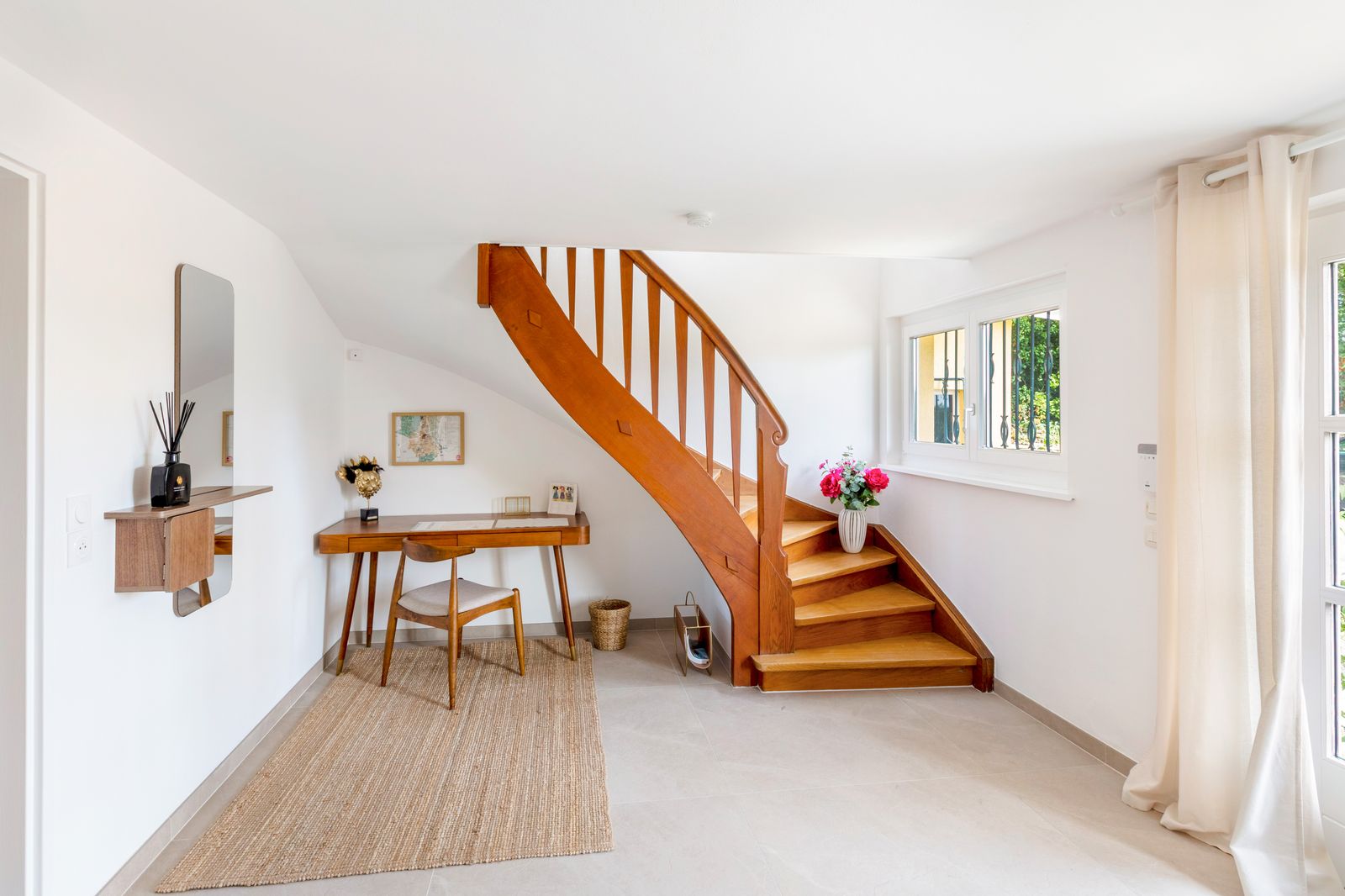 L’entrée et son escalier en bois tournant, petit bureau sous la fenêtre