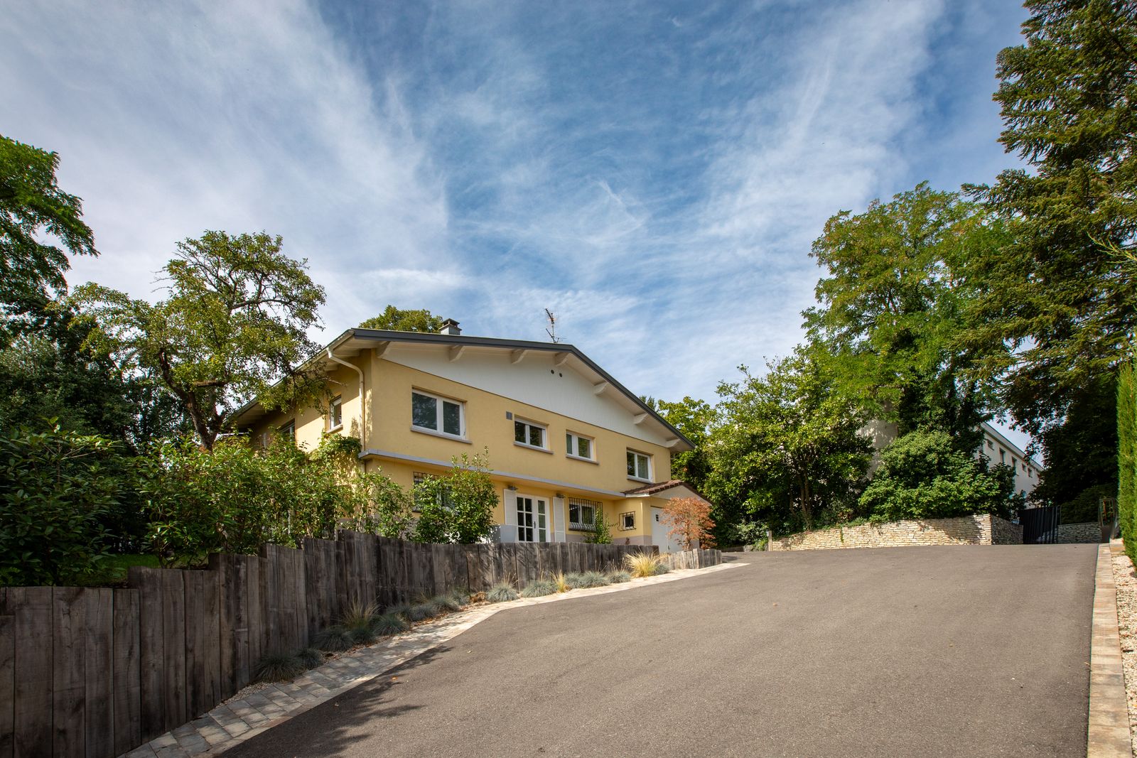 La villa vue de la rue, haie et grands arbres